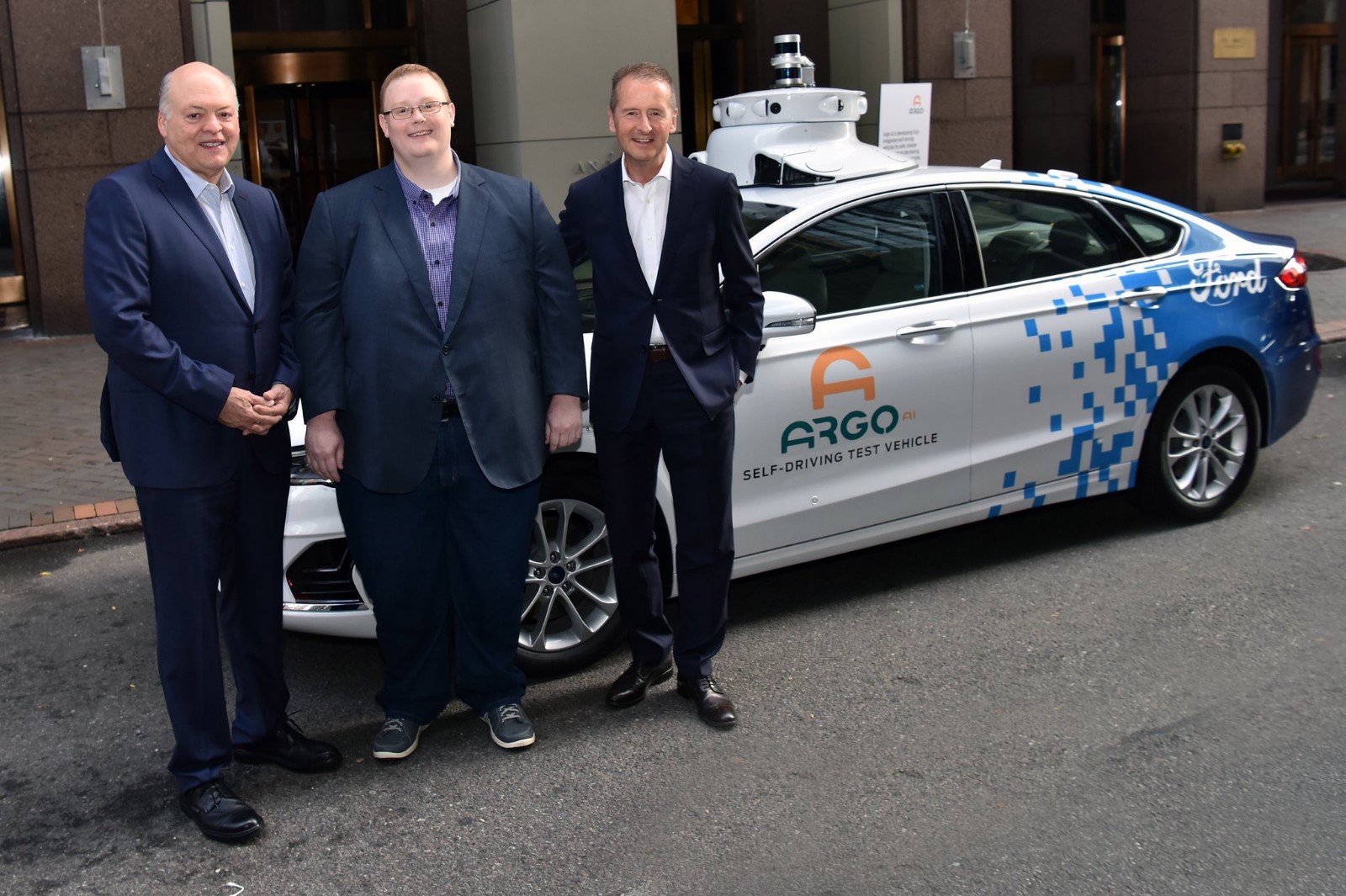 从左至右：福特汽车总裁兼CEO韩恺特、Argo AI创始人兼首席执行官布莱恩•塞尔斯基（Brian Salesky）、大众汽车集团CEO迪斯博士与福特/Argo AI基于美版蒙迪欧（Fusion）混动版打造的L4级自动驾驶测试车前合影
